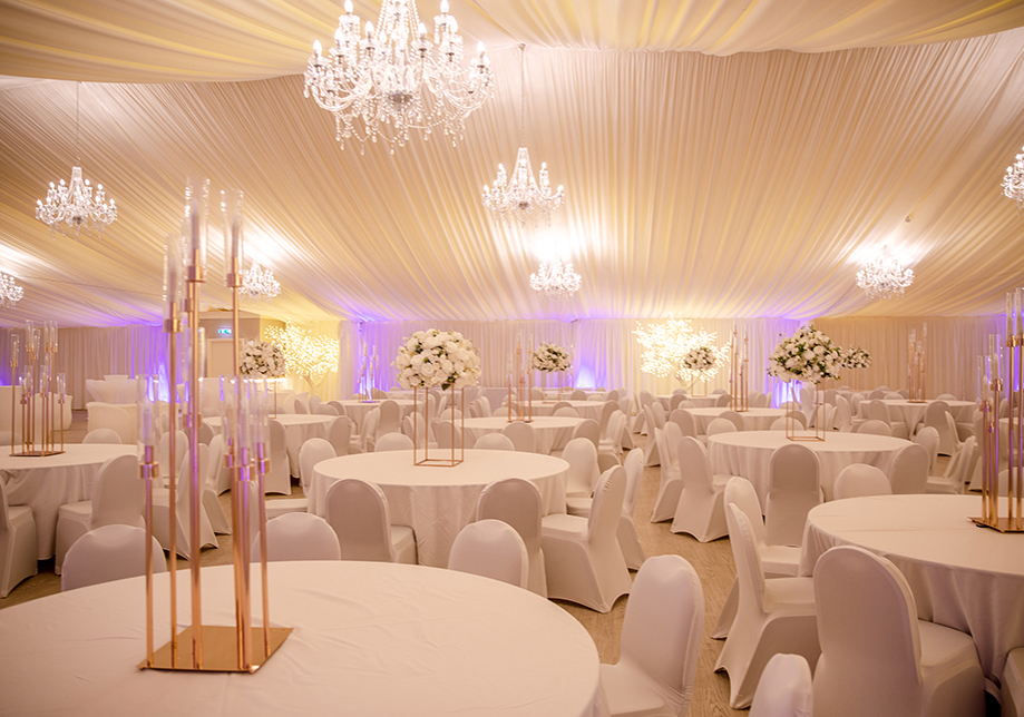 Round tables with white decor, draped ceiling and chandeliers